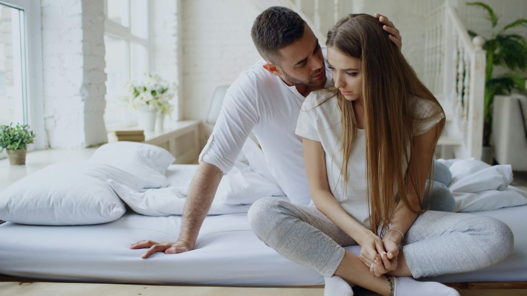 Couple sitting on a bed during a serious conversation